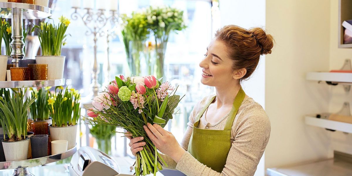 Floristin bindet lächelnd an der Kasse ein Strauß Blumen zusammen